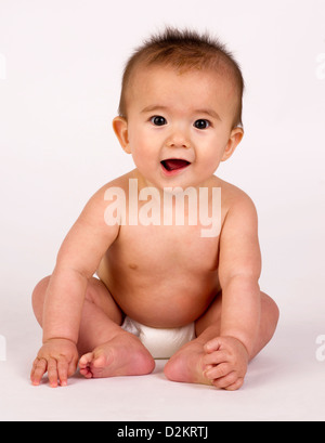 Cute Infant garçon dans une composition verticale se trouve maintenant ses orteils sur blanc Banque D'Images