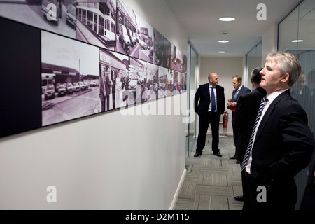Un homme en costume se tient et admire une collection de photographies en noir et blanc sur l'affichage. Banque D'Images