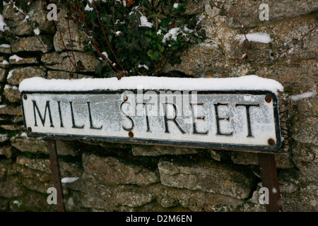 Rue Mill Road sign, Oxford, Oxfordshire, Angleterre. La neige tombe et la neige se pose sur le sol et mur en pierre sèche. Banque D'Images