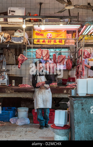 Boucher dans sa boutique de bouchers sur Des Voeux Road (Rue de fruits de mer séchés), Sheung Wan, Hong Kong. Banque D'Images