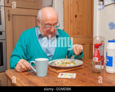 Homme âgé manger repas à table à manger Banque D'Images