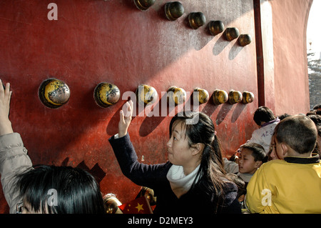 Les touristes sur les boutons d'or touch porte dans la Cité interdite pour la chance. Beijing, Chine. Banque D'Images