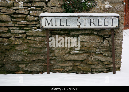 Rue Mill Road sign, Oxford, Oxfordshire, Angleterre. La neige tombe et la neige se pose sur le sol et mur en pierre sèche. Banque D'Images