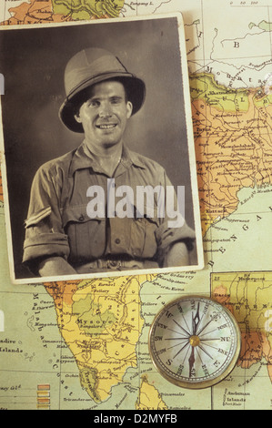 Photographie en noir et blanc d'homme en uniforme militaire tropical placé avec boussole sur la carte de l'Inde Banque D'Images