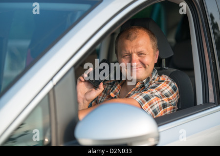 Jeune homme et voiture conduite holding smart phone dans la main droite Banque D'Images