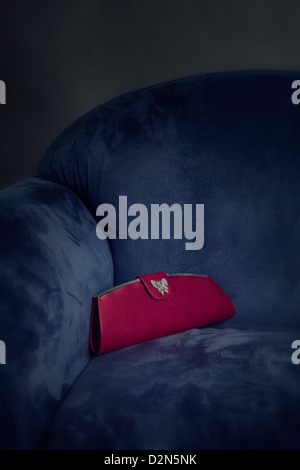 Un sac à main rouge couché sur un fauteuil bleu Banque D'Images