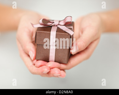 Closeup of woman's hands holding petit cadeau avec ruban Banque D'Images