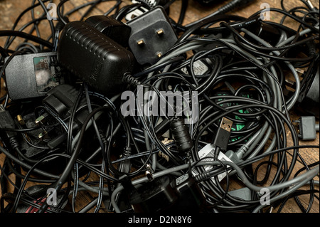 Une pile de vieux chargeurs de téléphones redondants et d'autres adaptateurs d'alimentation électrique et les câbles câbles UK Banque D'Images