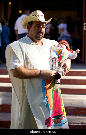 Homme en tenue traditionnelle tenant son bébé fils lors de la célébration de l’anniversaire de la Virgen de Guadalupe au Mexique Banque D'Images