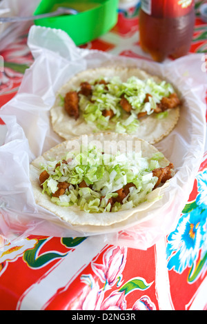 Tacos de poisson fraîchement préparés recouverts de laitue râpée, servis sur une nappe colorée à Mazatlán, Sinaloa, Mexique Banque D'Images