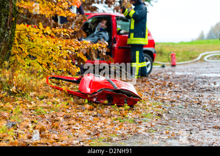 Accident - fire brigade sauve une victime d'accident d'une voiture, une porte de la voiture se trouvant sur la chaussée glissante Banque D'Images