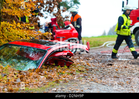 Accident - fire brigade sauve une victime d'accident d'une voiture, une porte de la voiture se trouvant sur la chaussée glissante Banque D'Images