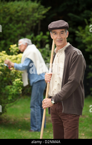 Senior couple ramasser des feuilles dans le jardin Banque D'Images