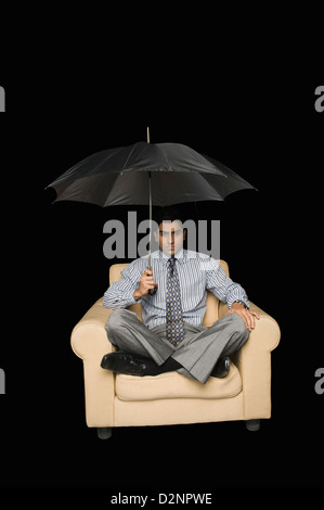 Portrait dans un fauteuil sous parapluie ouvert Banque D'Images