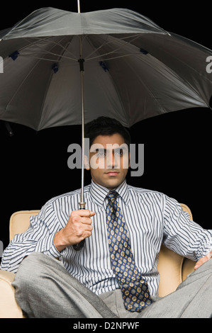 Portrait dans un fauteuil sous parapluie ouvert Banque D'Images