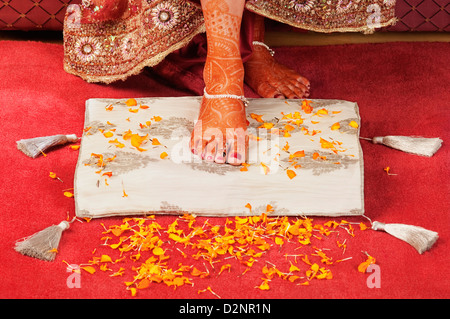 Pied de la mariée sur un coussin avec pétales de fleurs Banque D'Images