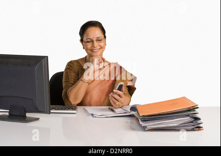 Businesswoman using a mobile phone in an office Banque D'Images