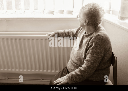 Femme de quatre-vingt-dix ans avec radiateur à la main regardant hors de la fenêtre, Royaume-Uni. Coronavirus, auto-isolement, distanciation sociale, quarantaine... concept Banque D'Images