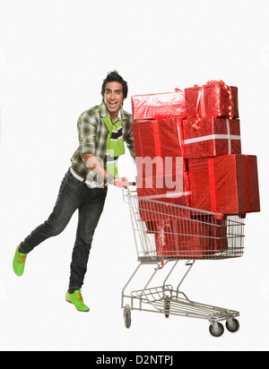 L'homme en poussant un panier rempli de cadeaux Banque D'Images