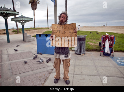 Les sans-abri guy sur Venice Beach Ocean Front Walk avec drôle signe, 2010 Banque D'Images