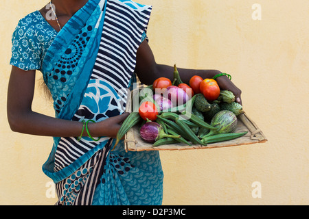 Village de l'Inde rurale femme tenant un plateau de légumes indiens dans ses mains. L'Andhra Pradesh, Inde Banque D'Images