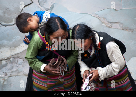Les femmes tibétaines en costume traditionnel de rire, enfant endormi sur le dos, Lhassa, Tibet, Chine Banque D'Images