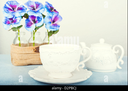 Tasse à thé sur une table en bois à l'arrière-plan pensées dans un vase Banque D'Images