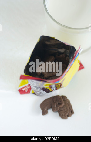 Les cookies au chocolat en forme d'animal avec un paquet sur une serviette en papier blanc et le verre de lait de vache le haut point de vue Banque D'Images