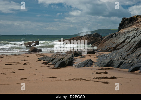 Vagues se brisant sur des rochers et une plage de sable Banque D'Images