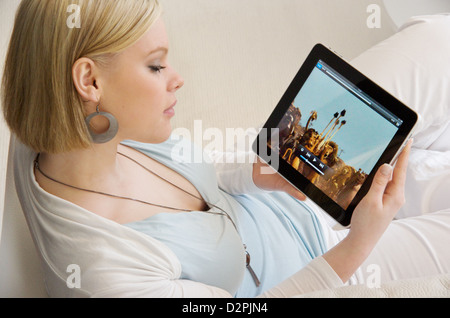 Hambourg, Allemagne, une jeune femme assise sur le canapé avec son iPad Banque D'Images