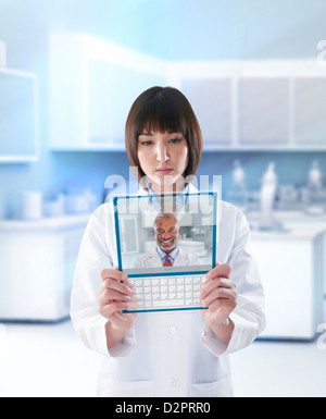 Mixed Race doctor using digital tablet in doctor's office Banque D'Images