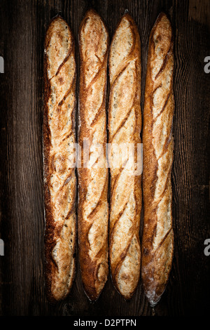 Ensemble de quatre pains baguette sur fond de bois foncé Banque D'Images