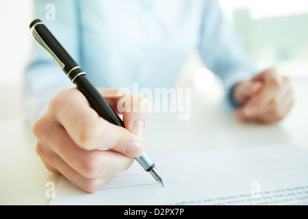 Image en gros plan d'une femme d'affaires à mettre sa signature Banque D'Images