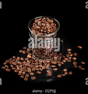 Mug en verre avec les grains de café rôtis entiers sur fond noir Banque D'Images