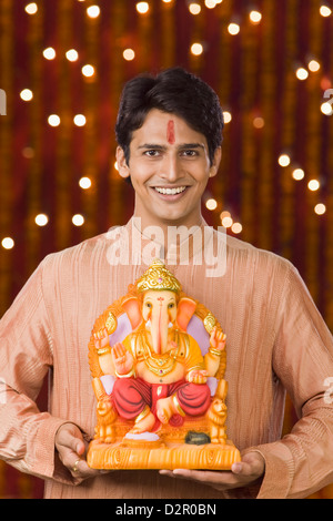 Portrait d'un homme tenant une idole du Seigneur Ganesha Banque D'Images