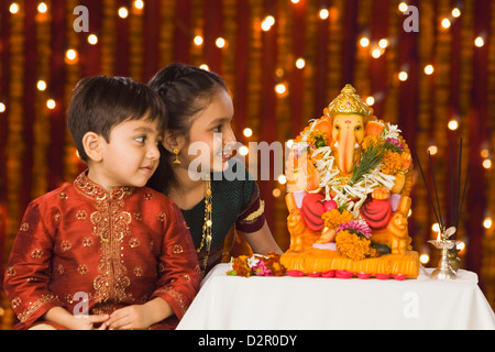 Deux enfants assis en face de l'idole de Seigneur Ganesha Banque D'Images