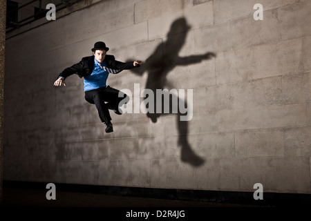 Parkour runner en chapeau melon avec l'ombre, sautant Banque D'Images