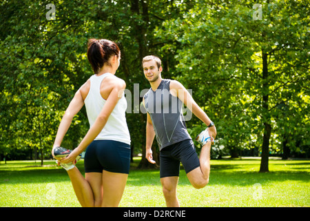 Jeune couple l'exercice et les étirements muscles avant l'activité sportive - piscine dans la nature Banque D'Images