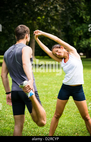 Jeune couple l'exercice et les étirements muscles avant l'activité sportive - piscine dans la nature Banque D'Images