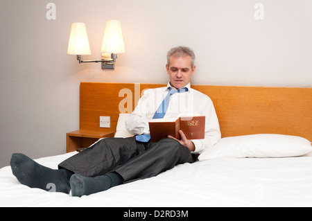 L'homme d'affaires en chambre d'hôtel reading Gideons Holy Bible Banque D'Images