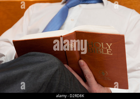 L'homme d'affaires en chambre d'hôtel reading Gideons Holy Bible Banque D'Images