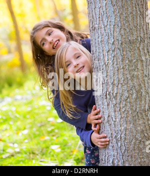 Kid sister automne filles jouant en forêt près de Poplar tree trunk dans nature plein air Banque D'Images