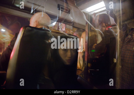 Femme Asiatique en miroir dans la fenêtre derrière le conducteur d'un bus surpeuplés à Paris Banque D'Images