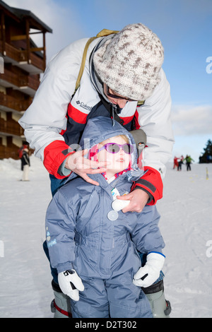 Mère / mère / l'application de crème solaire s'applique sur le visage de sa jeune fille, alors qu'enfant le long d'une pente de ski de haute altitude. Banque D'Images