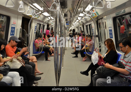 Voyageurs assis à l'intérieur d'un train de métro MRT Singapour transport et la visualisation de leurs téléphones, etc. Banque D'Images