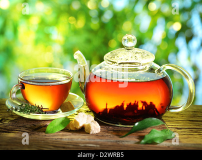 Tasse de thé et une théière sur un arrière-plan flou de la nature. Banque D'Images