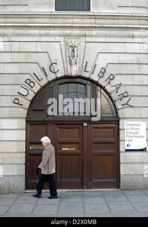 Femme âgée passant une ancienne bibliothèque publique marqué d'entrée, porchester hall, Bayswater, Londres, Angleterre Banque D'Images