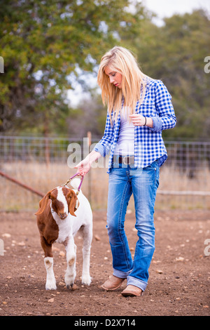 Fille qui marche sur l'élevage de chèvres farm Banque D'Images