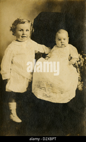 Circa 1910 photographie tout-petits, et son petit frère ou sœur en robe de style édouardien. Banque D'Images