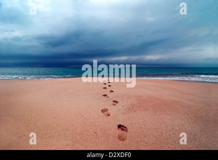 Grosse tempête avec nuages sur des empreintes de pas dans le sable mou qui mène à l'océan, plage Papohaku, Molokai, Hawaï, USA, l'Océan Pacifique Banque D'Images
